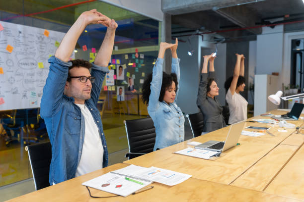 People stretching while sitting at a desk